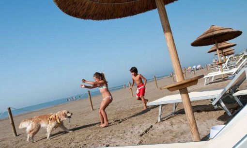 eti so psom sa hrajú na pláži na ostrove Grado v Taliansku