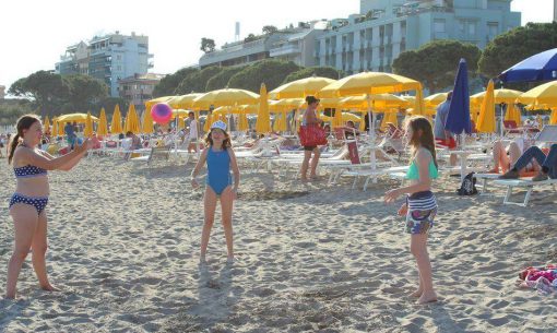 slnečníky a deti na pláži v talianskom Grade